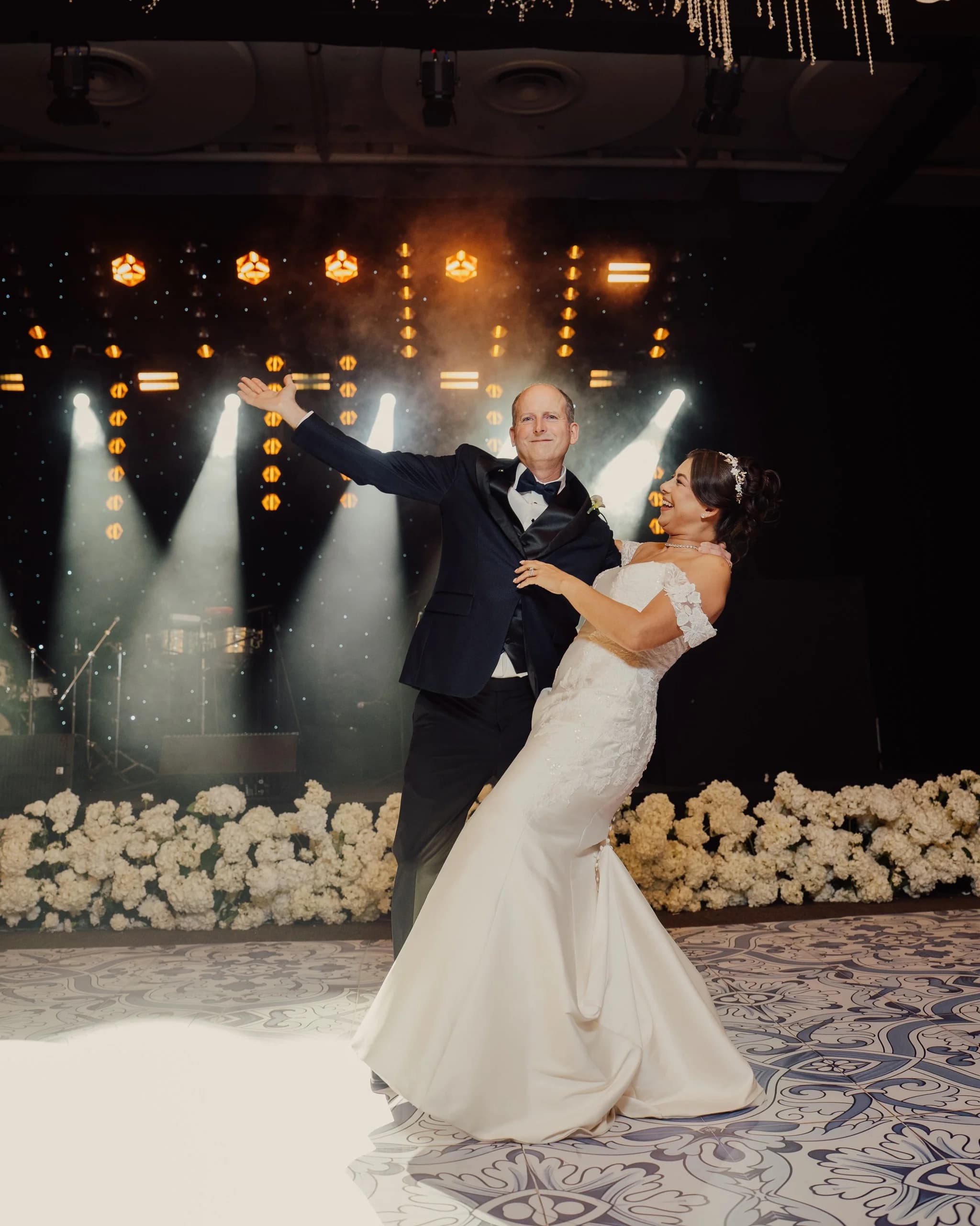 A newlywed couple performing their choreographed first dance under stage lights